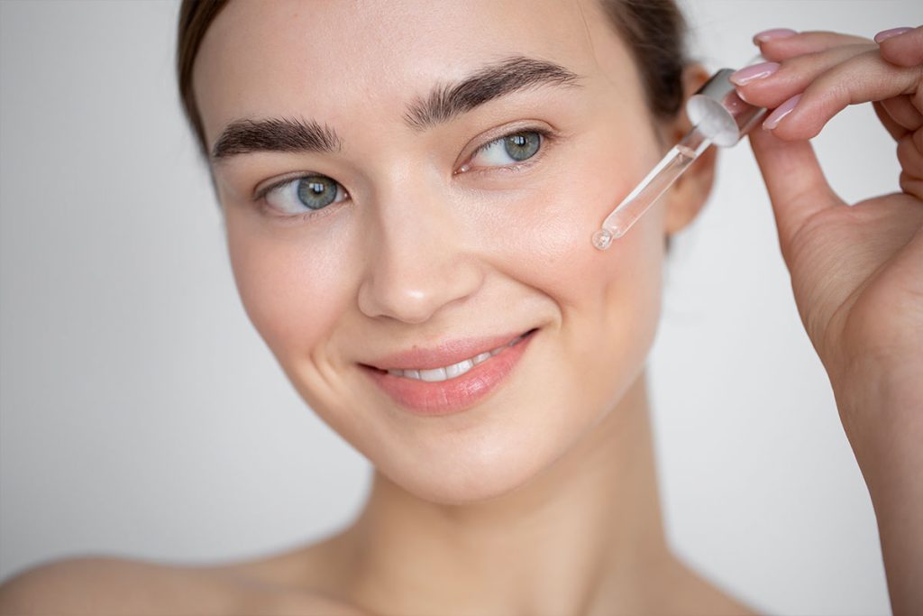 donna che applica trattamento siero viso all'acido ialuronico