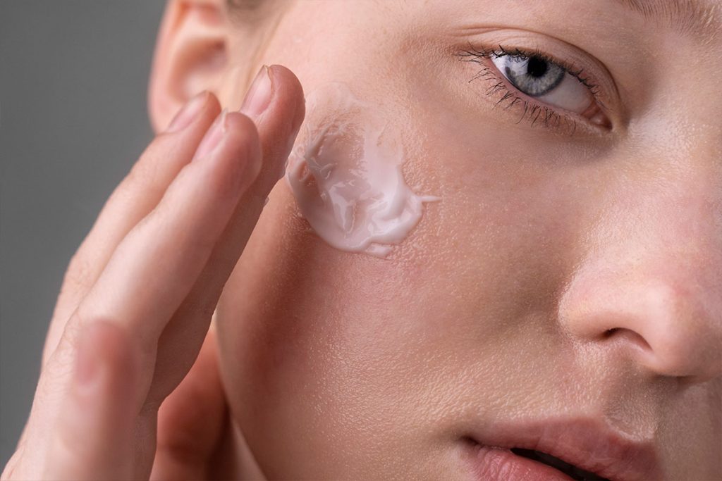 donna che applica trattamento crema viso