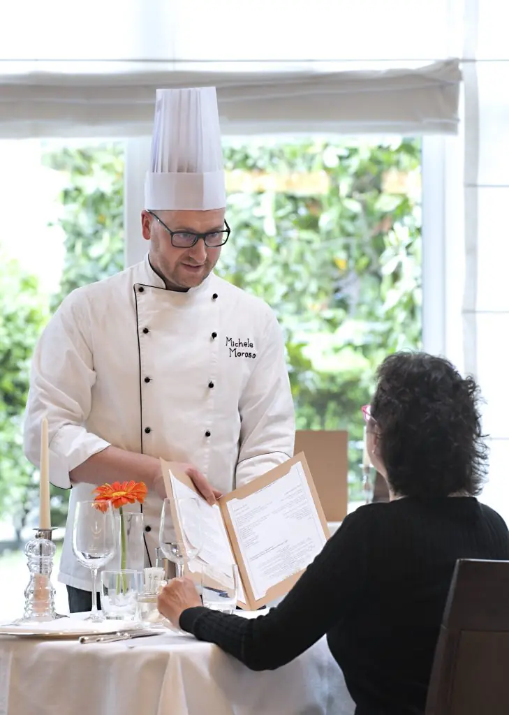 chef mostra menù ristorante a uomo